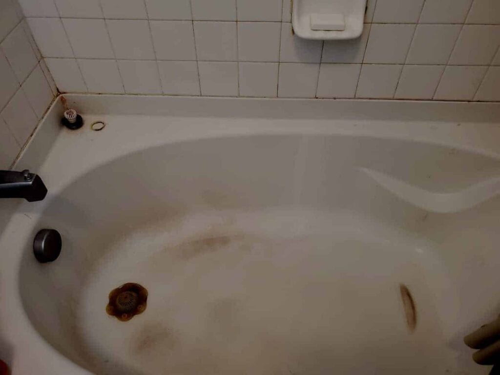 A used bathtub with rust stains and grime, a bathroom water problem affected by dirt and corrosion.