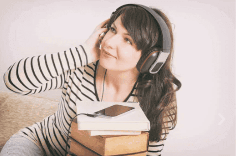 Woman using headphones with water-themed books.