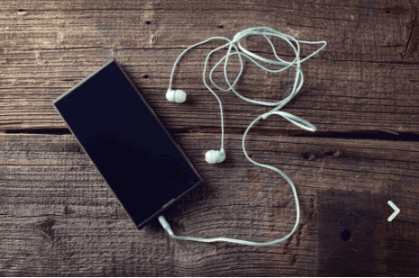 Smartphone with earphones on wooden surface for daily water activity.