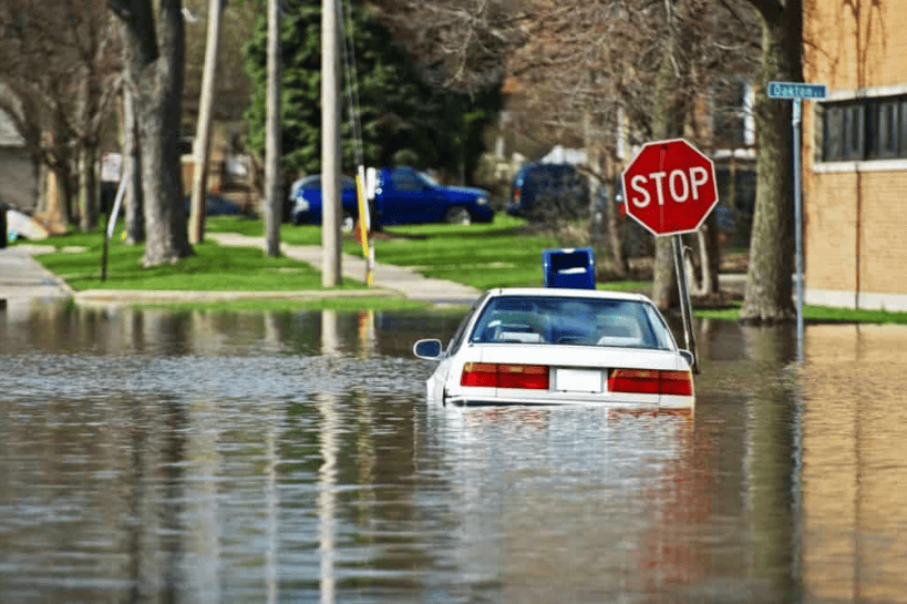 Flooded vehicle submerged in street water during flooding event.