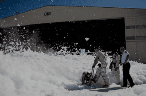 Emergency responders clearing snow with a blower outside a building.